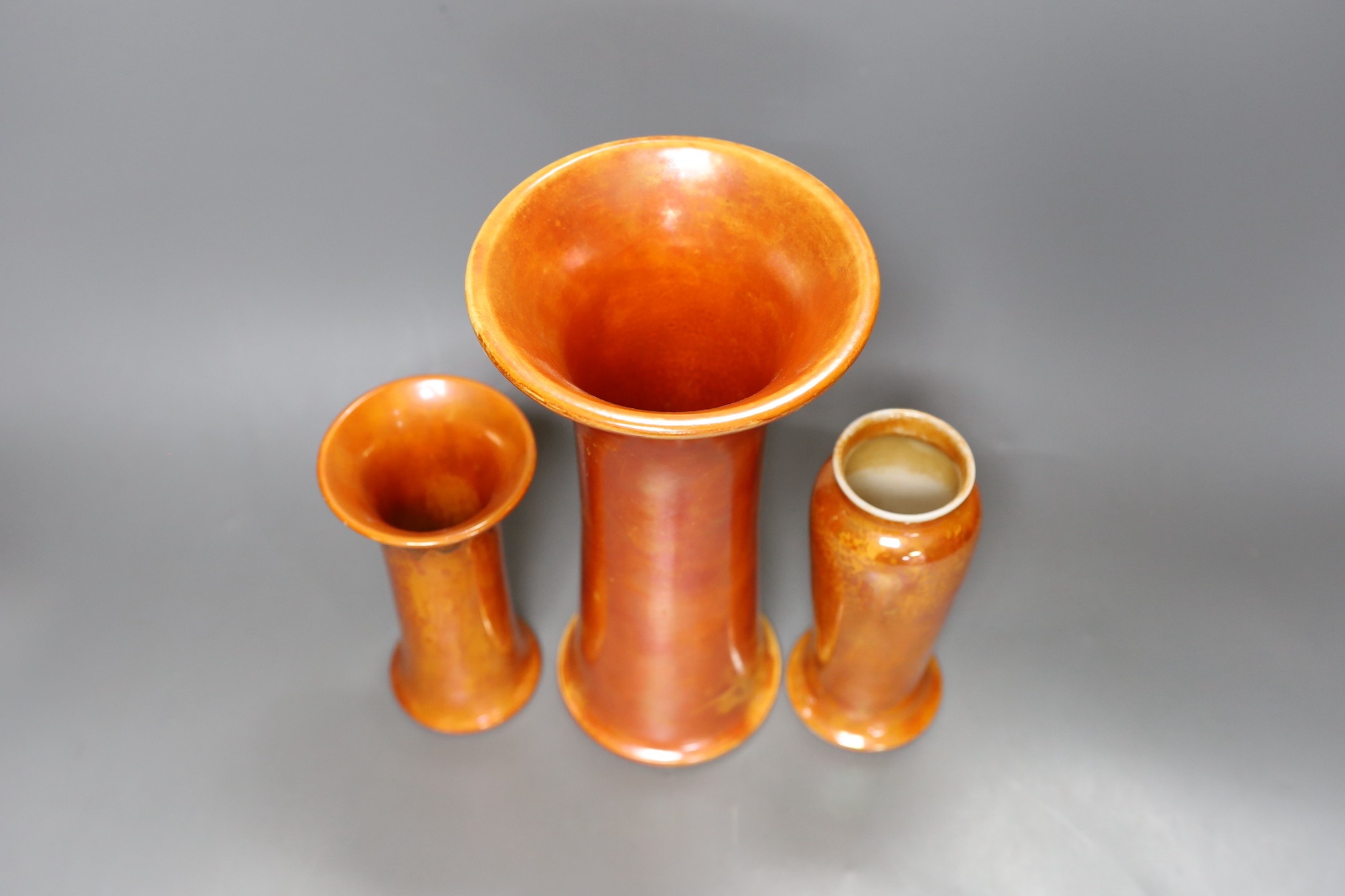 A group of three Ruskin orange lustre vases, largest 25cm